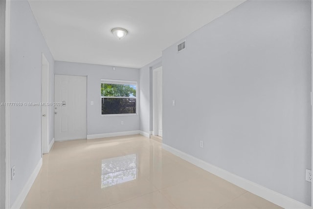spare room with light tile patterned floors, visible vents, and baseboards