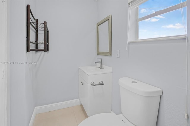 half bath with tile patterned flooring, toilet, vanity, and baseboards