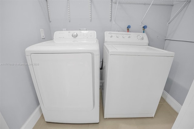 clothes washing area with laundry area, baseboards, and washer and clothes dryer