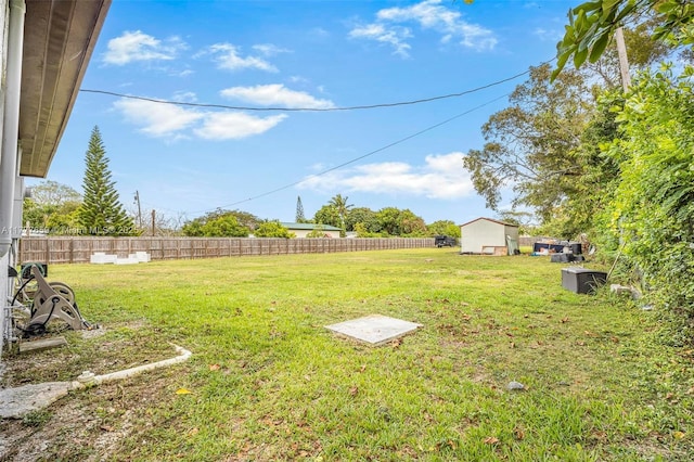 view of yard featuring an outdoor structure, fence, and a storage unit