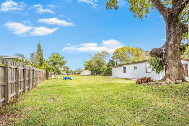 view of yard with an outdoor structure, fence, and a storage unit