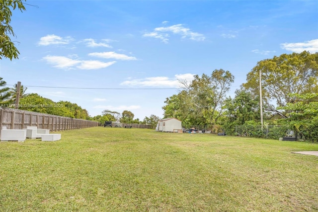 view of yard with a storage shed, a fenced backyard, and an outdoor structure