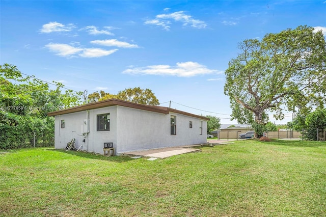 rear view of property featuring a yard, fence, a patio area, and stucco siding