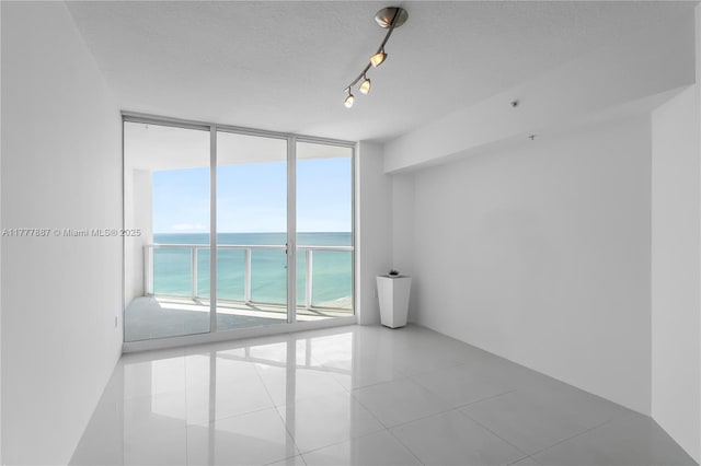 16699 Collins Ave Unit 1610, Sunny Isles Beach, FL 33160 - empty room featuring floor to ceiling windows, a water view, a textured ceiling, and tile patterned floors