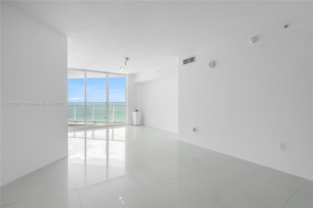 16699 Collins Ave Unit 1610, Sunny Isles Beach, FL 33160 - unfurnished room with a wall of windows, a water view, tile patterned flooring, and a textured ceiling