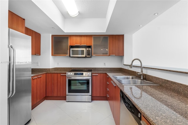 16699 Collins Ave Unit 1610, Sunny Isles Beach, FL 33160 - kitchen with appliances with stainless steel finishes, a raised ceiling, brown cabinetry, dark stone counters, and glass insert cabinets