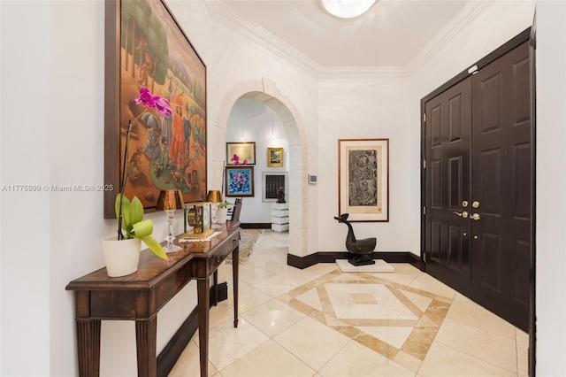 foyer entrance featuring crown molding, light tile patterned flooring, baseboards, a high ceiling, and arched walkways
