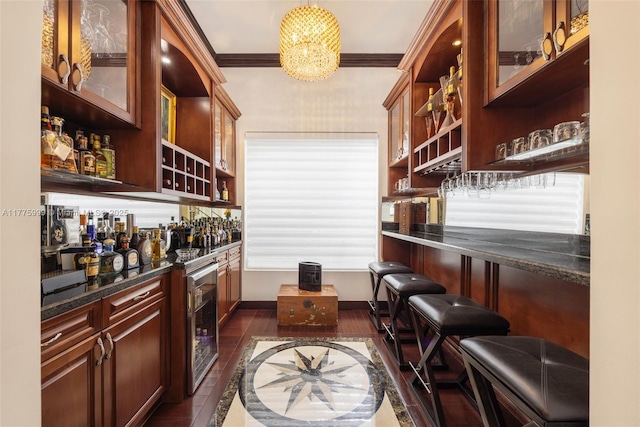 bar featuring ornamental molding, baseboards, dark wood-type flooring, a dry bar, and a notable chandelier