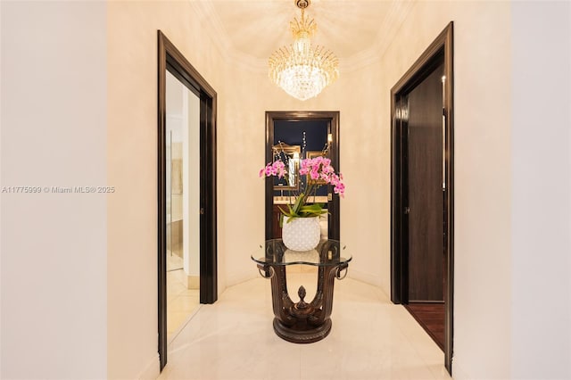 corridor with tile patterned floors, ornamental molding, baseboards, and a chandelier