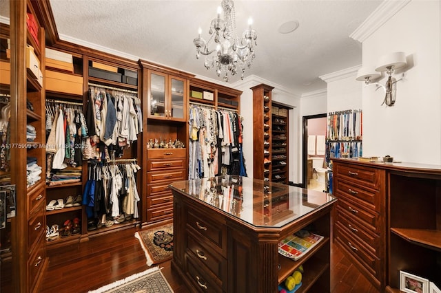 spacious closet with a chandelier and dark wood-style floors