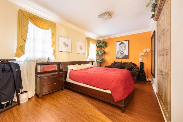 bedroom with ornamental molding and wood finished floors