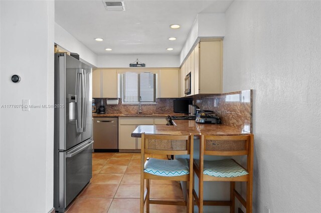 2447 SE 15th St, Pompano Beach, FL 33062 - kitchen featuring light tile patterned floors, cream cabinets, visible vents, appliances with stainless steel finishes, and a sink