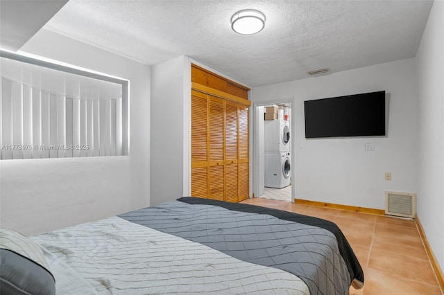 2447 SE 15th St, Pompano Beach, FL 33062 - tiled bedroom with stacked washer / dryer, a closet, visible vents, and a textured ceiling