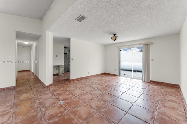 unfurnished room with a textured ceiling, light tile patterned floors, baseboards, and visible vents