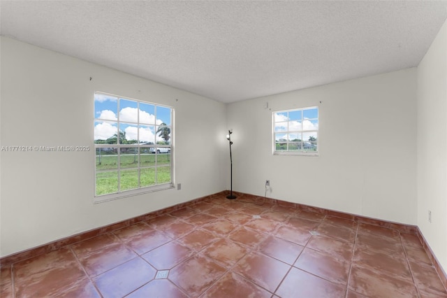empty room featuring a textured ceiling and baseboards