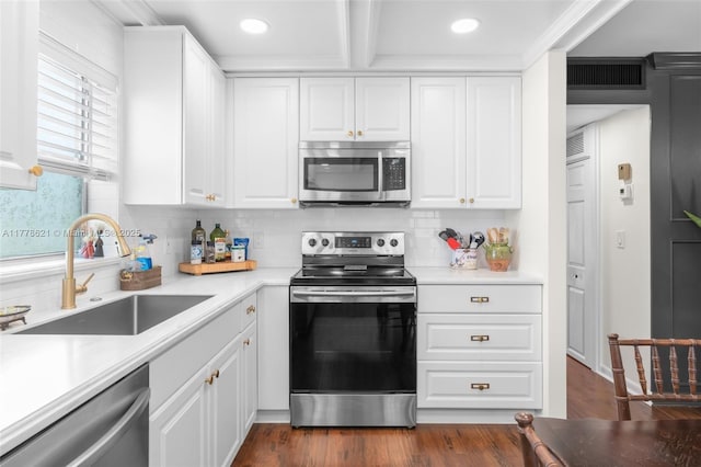 kitchen with white cabinets, a sink, appliances with stainless steel finishes, and dark wood-style flooring