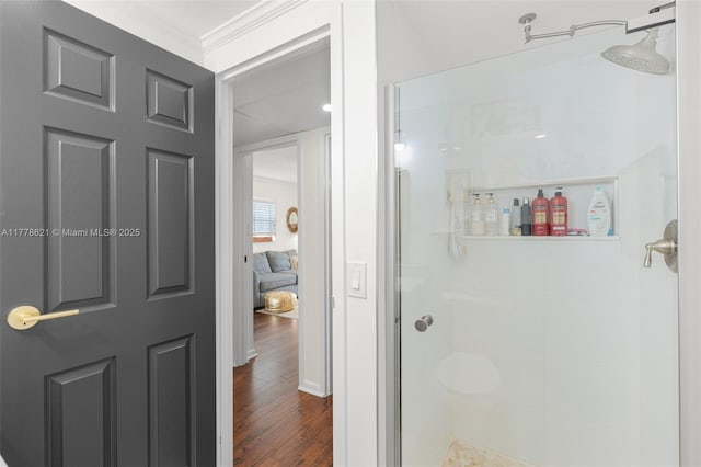 bathroom featuring a shower stall, ornamental molding, and wood finished floors