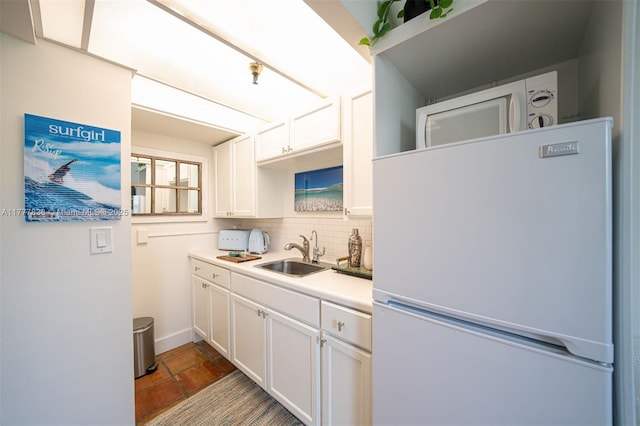 kitchen featuring freestanding refrigerator, a sink, backsplash, and white cabinets