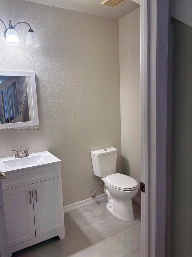 half bathroom with tile patterned floors, toilet, vanity, and baseboards
