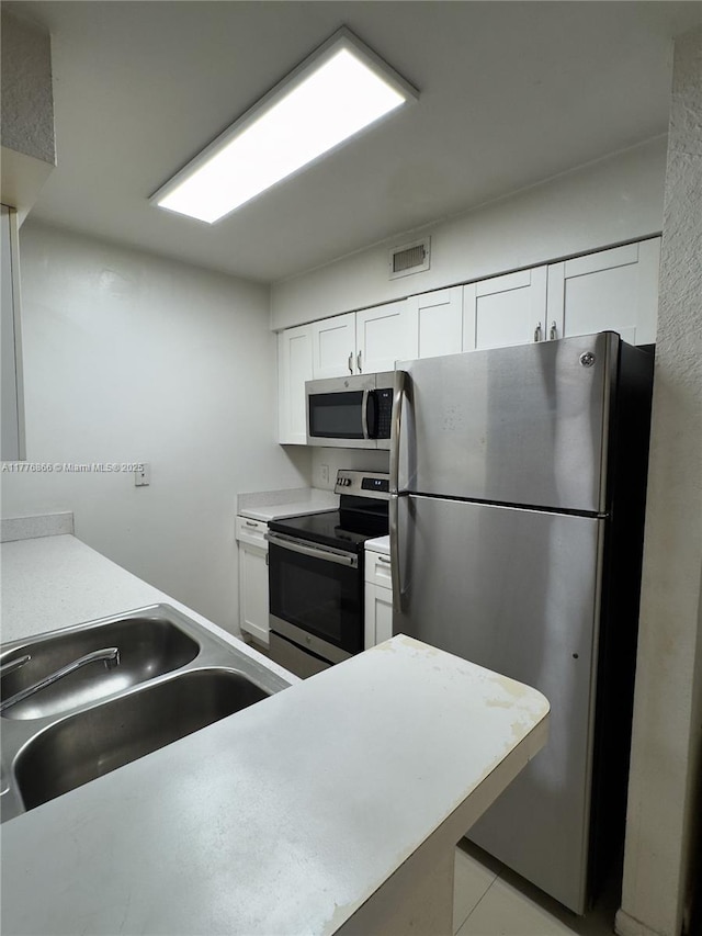 kitchen with white cabinets, visible vents, a sink, light countertops, and stainless steel appliances