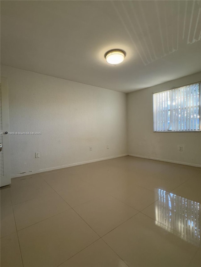 spare room with tile patterned floors and baseboards