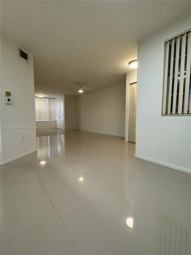 spare room with tile patterned flooring, visible vents, and baseboards