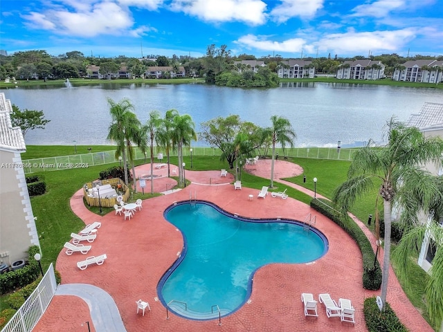 community pool featuring a water view, fence, a patio, and a lawn