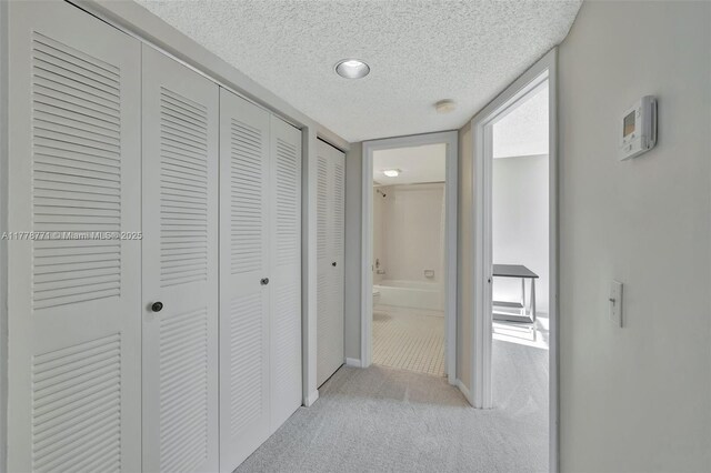 12701 SW 13th St Unit 301F, Pembroke Pines, FL 33027 - hallway featuring a textured ceiling, baseboards, and light carpet