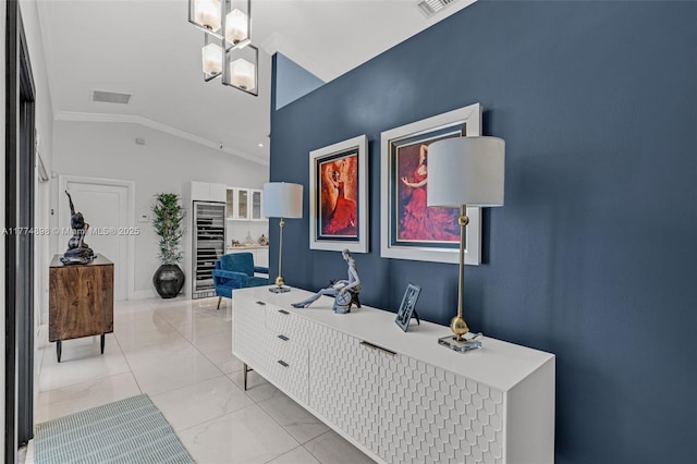 interior space with an inviting chandelier, ornamental molding, marble finish floor, beverage cooler, and lofted ceiling