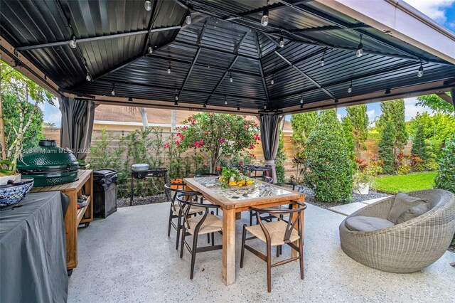 view of patio featuring a gazebo, outdoor dining area, and fence