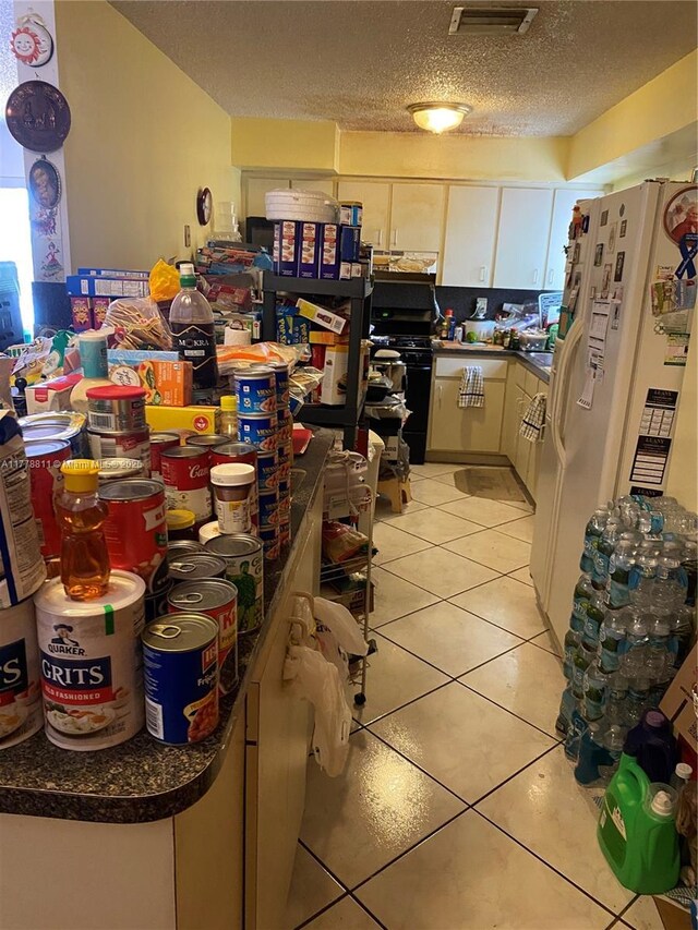 10041 SW 14th Ter, Miami, FL 33174 - kitchen with white fridge with ice dispenser, light tile patterned floors, a textured ceiling, dark countertops, and black gas range oven