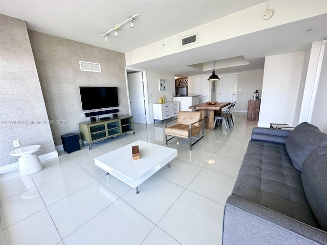 living room featuring visible vents, an accent wall, light tile patterned flooring, and baseboards