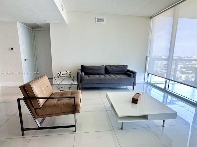 tiled living area with visible vents, baseboards, and a wall of windows