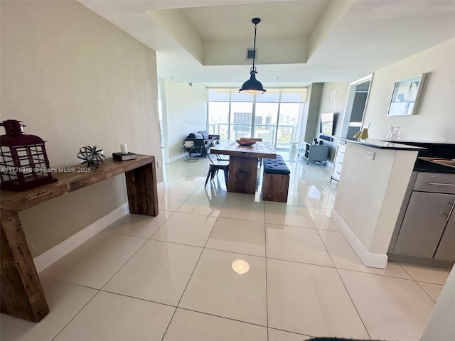 kitchen featuring a tray ceiling, baseboards, and light tile patterned floors
