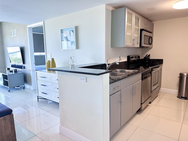 kitchen with light tile patterned floors, visible vents, a sink, dark countertops, and appliances with stainless steel finishes