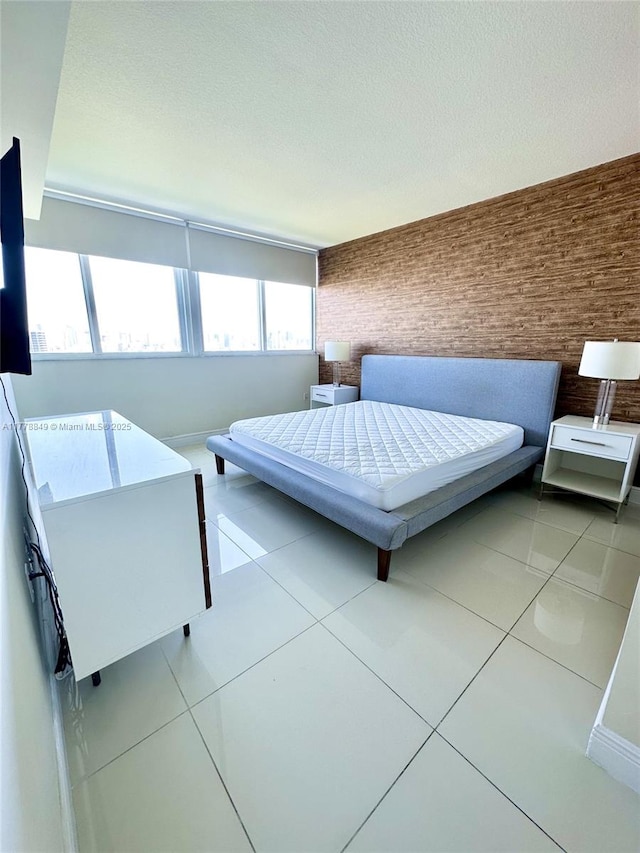 unfurnished bedroom featuring tile patterned flooring, brick wall, and a textured ceiling