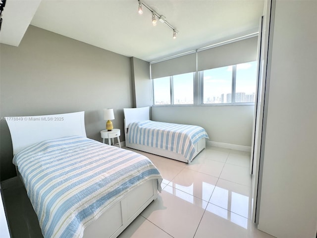 bedroom featuring track lighting, light tile patterned floors, and baseboards