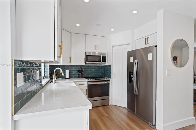 kitchen with white cabinetry, light wood-type flooring, appliances with stainless steel finishes, and a sink