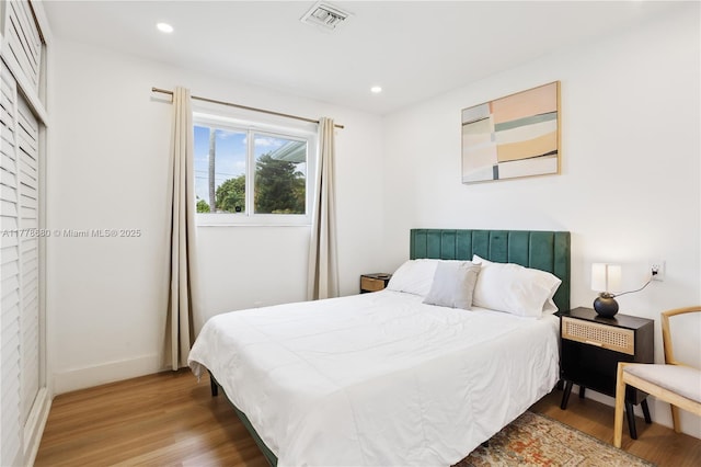 bedroom featuring baseboards, visible vents, wood finished floors, and recessed lighting