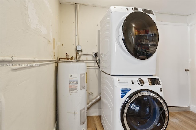 clothes washing area featuring stacked washer / dryer, water heater, laundry area, and light wood-type flooring