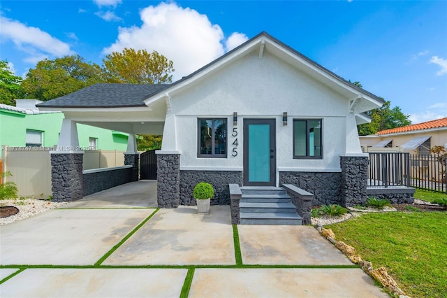view of front of home featuring a carport, stucco siding, stone siding, and fence
