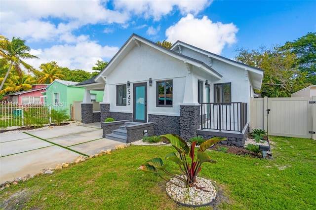view of front facade featuring a front lawn, fence, a gate, and stucco siding