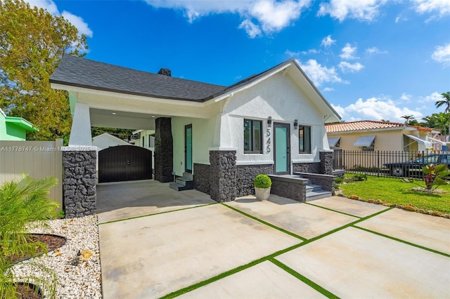 view of front of home featuring stucco siding, stone siding, fence, a gate, and concrete driveway