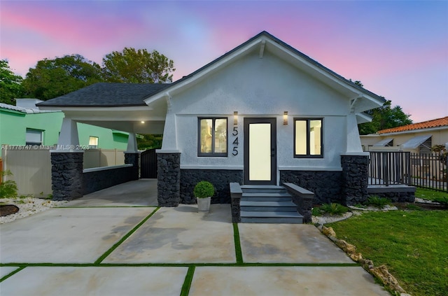 view of front facade with an attached carport, stucco siding, and fence