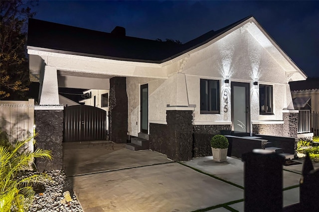 view of front of home with stone siding, stucco siding, fence, and a gate