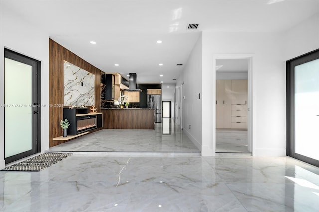 kitchen with stainless steel fridge with ice dispenser, modern cabinets, ventilation hood, a fireplace, and marble finish floor