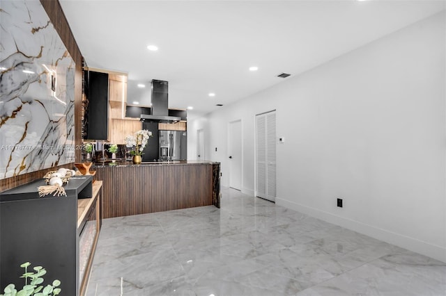 kitchen featuring a peninsula, stainless steel refrigerator with ice dispenser, visible vents, island range hood, and marble finish floor