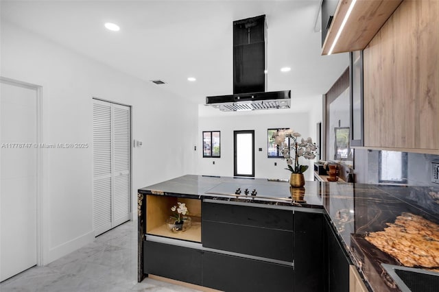 kitchen featuring modern cabinets, dark cabinets, a peninsula, visible vents, and extractor fan
