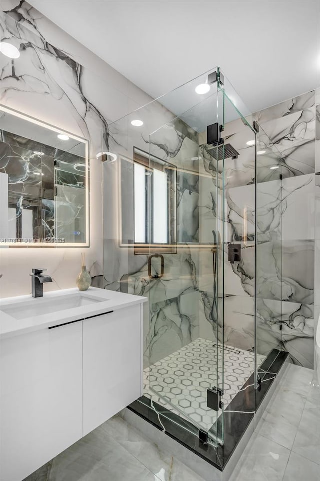 full bathroom with stone wall, marble finish floor, vanity, and a marble finish shower