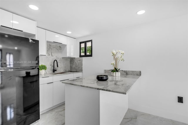 kitchen with modern cabinets, tasteful backsplash, a peninsula, white cabinetry, and marble finish floor